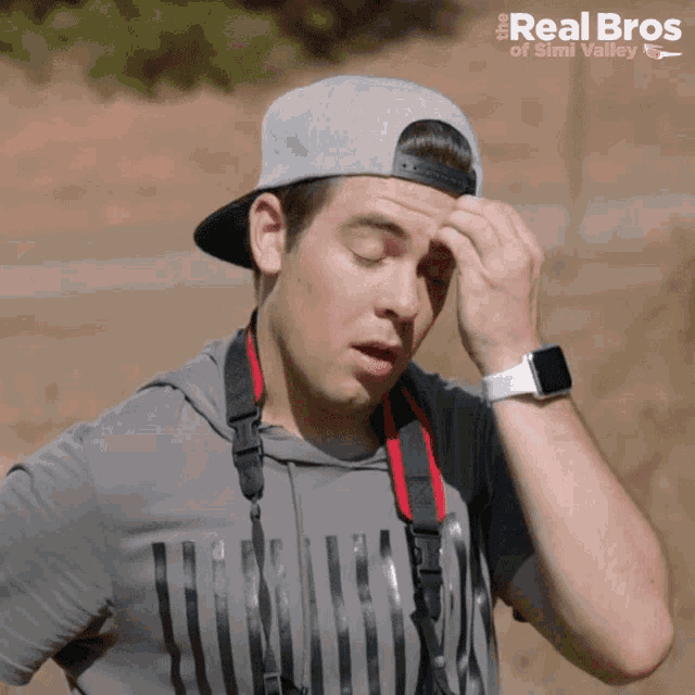a man wearing a hat and a shirt that says real bros on it