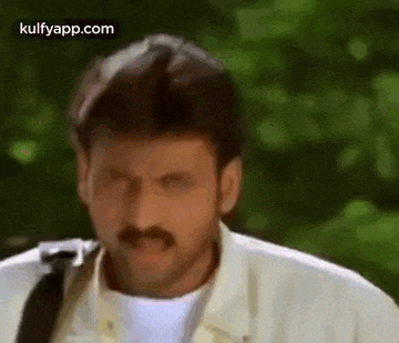 a man with a mustache and a white shirt is making a funny face .