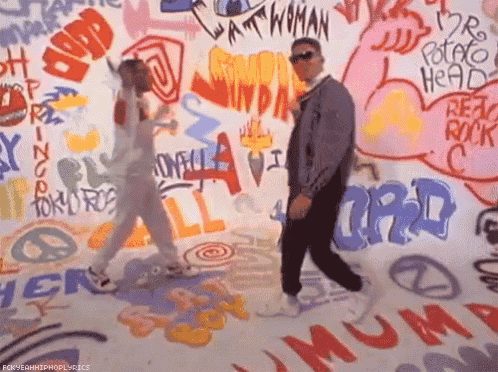 a man and woman are dancing in front of a wall that has graffiti on it including the word potato head