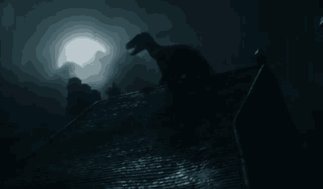 a silhouette of a dinosaur standing on top of a building at night .