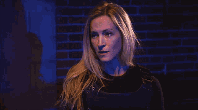a woman is standing in front of a brick wall