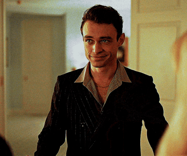 a man in a suit and striped shirt is smiling