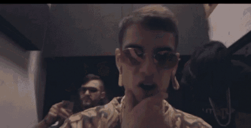 a man wearing sunglasses and ear plugs is standing next to another man