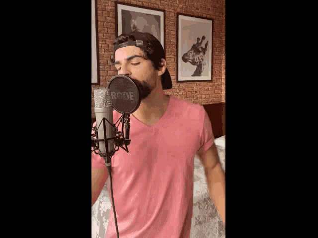 a man singing into a rode microphone in a bedroom