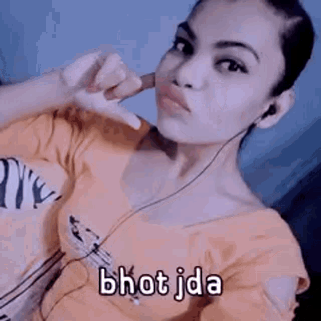 a woman is wearing headphones and making a hand gesture with the words bhot jada written on the bottom .