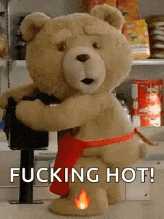a teddy bear is wearing a red apron and holding a gun and says `` fucking hot '' .