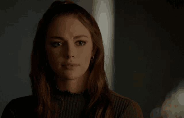 a woman in a green sweater is looking at the camera