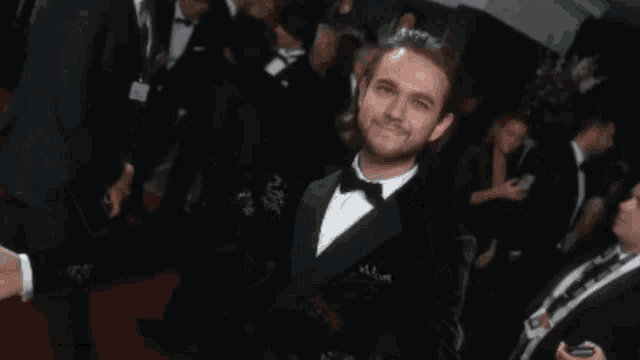 a man in a tuxedo is pointing at the camera and the name zedd is on the bottom