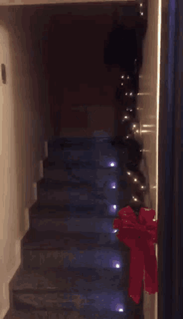 a man is walking down a set of stairs with a red bow on the side