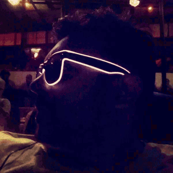 a man wearing glow in the dark sunglasses looks to the side