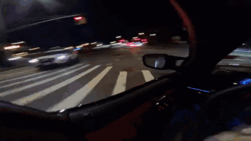 a person is driving down a street at night with a red light behind them