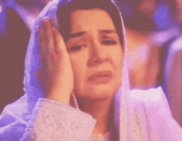 a woman wearing a veil is covering her face with her hands