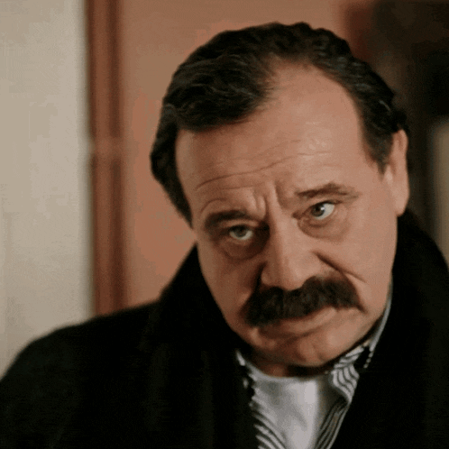 a man with a mustache is wearing a black jacket and striped shirt