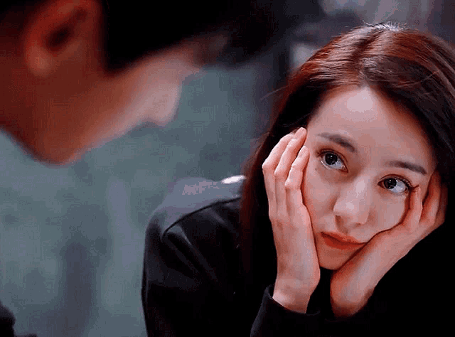 a woman with her hands on her face looks at the camera