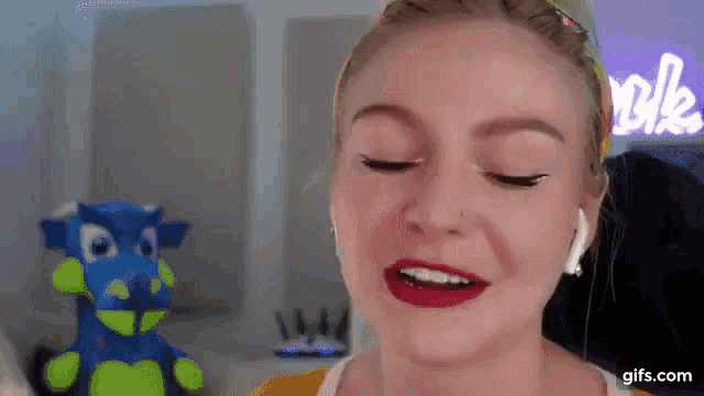 a close up of a woman 's face with a stuffed animal in the background and a sign that says love