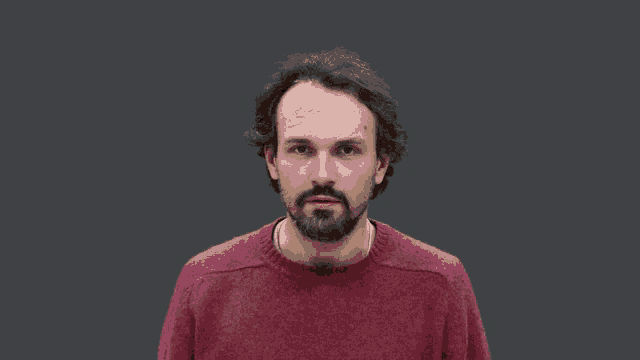 a man with a beard wearing a red sweater has his eyes closed