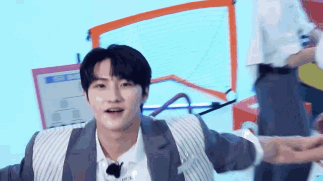 a young man in a suit and white shirt is standing in front of a basketball hoop .