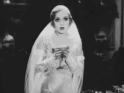a black and white photo of a woman in a bride 's dress holding a vase .