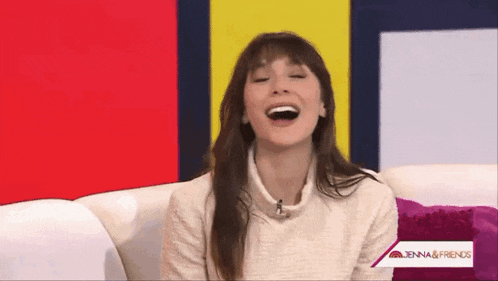 a woman is laughing while sitting on a couch in front of a sign that says jenna and friends