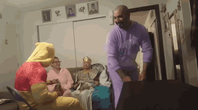 a man in purple pajamas stands in front of a group of people dressed as winnie the pooh