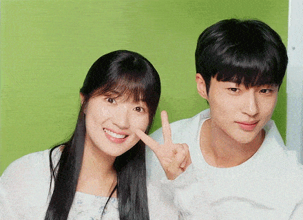 a man and a woman are posing for a picture together and the woman is giving a peace sign .
