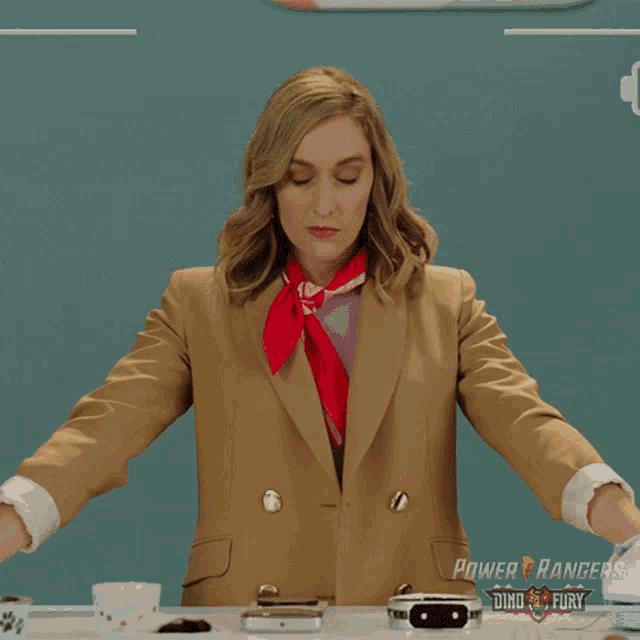 a woman wearing a power rangers jacket is sitting at a desk