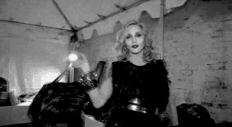 a black and white photo of a woman in a black dress standing in a room .