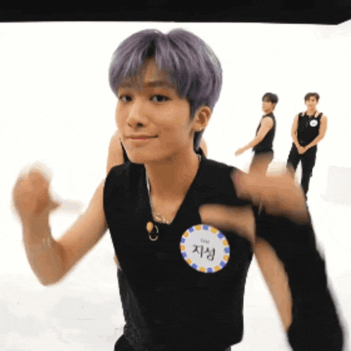 a man with purple hair is wearing a black tank top with a name tag