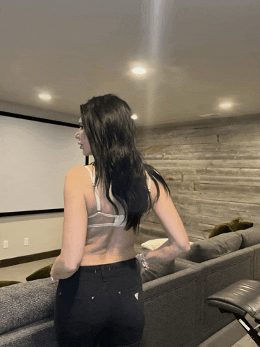 a woman is standing in front of a projector screen in a living room