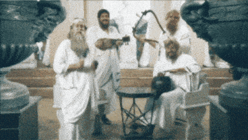 a group of men in white robes standing around a table