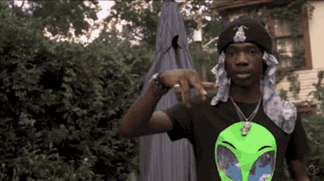 a man wearing a black beanie and a green shirt with an alien on it