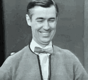 a black and white photo of a man wearing a bow tie and a sweater .