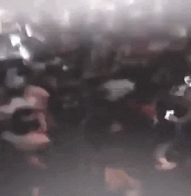 a blurry picture of a crowd of people dancing in a dark room .