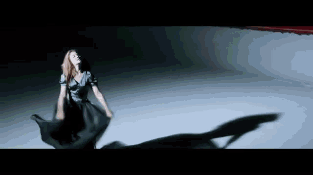 a woman in a black dress is dancing on a white surface