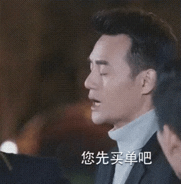 a man in a suit and turtleneck is talking to another man in a restaurant .