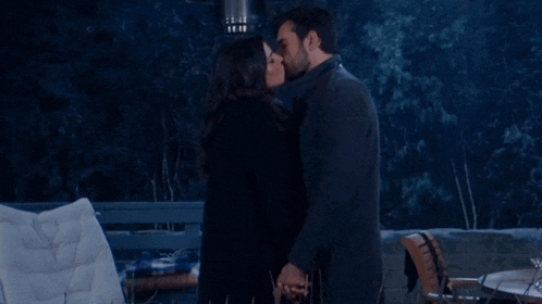 a man and a woman are kissing in front of a table