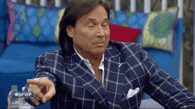a man in a plaid suit is pointing at something with #gfvip written on the bottom