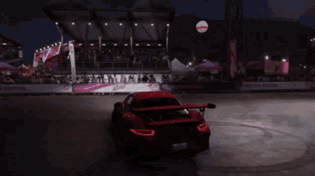a red car is doing a burnout in front of a crowd of people