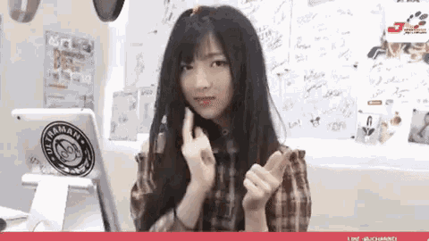 a young woman is making a peace sign with her hands in front of a white board .
