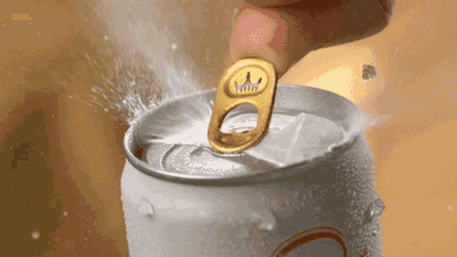 a person is opening a can of beer with a crown on the pull tab