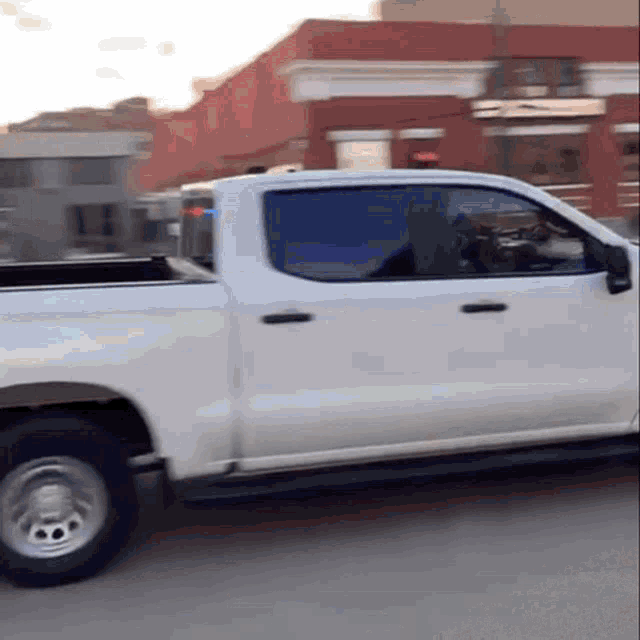 a white truck is driving down a street in front of a building