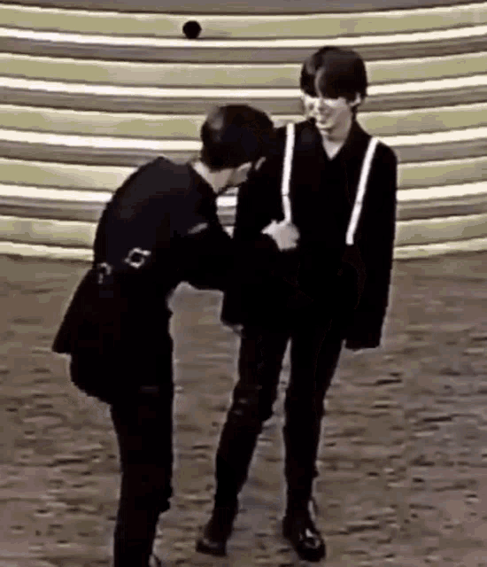 two men are standing next to each other on a stage and one of them is holding the other 's hand .