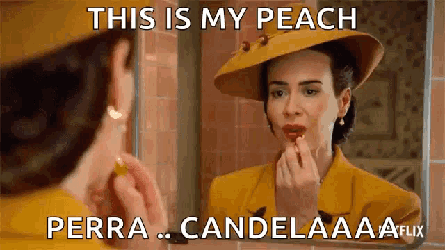 a woman is applying lipstick in front of a mirror while wearing a yellow suit and hat .