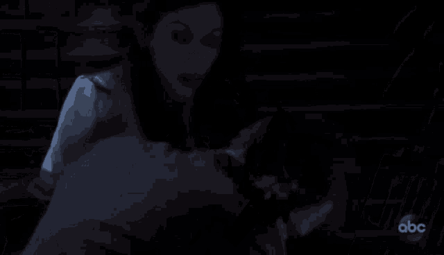 a man and a woman are fighting in a dark room with a pallet in the background .