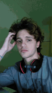 a young man wearing headphones and a blue shirt with a picture of a city on it