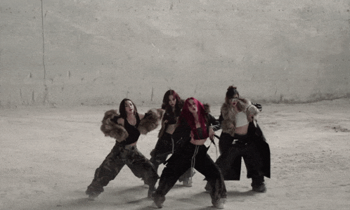 three women with red hair are dancing in front of a concrete wall