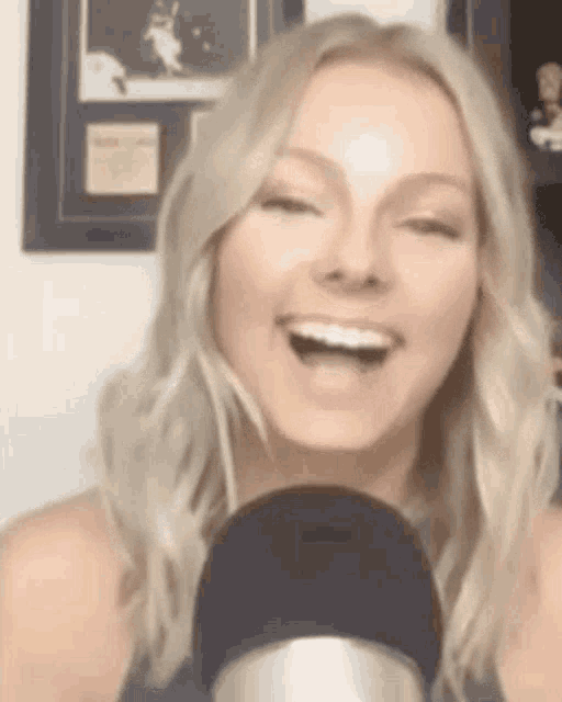 a woman is smiling in front of a microphone and laughing .