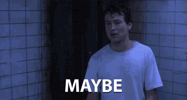a man in a white shirt is standing in a dark room with maybe written on the bottom