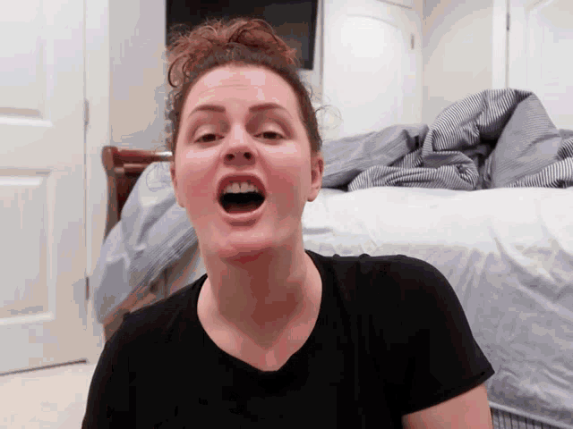 a woman making a funny face in front of a bed