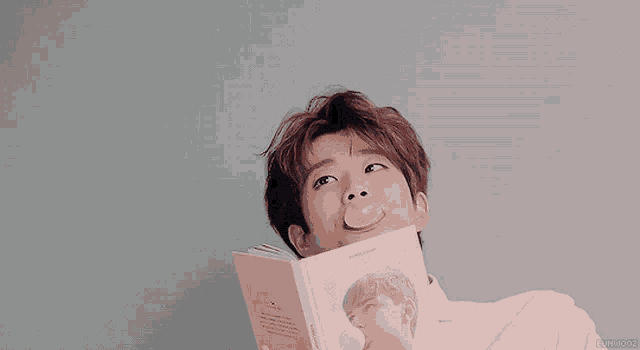 a man blowing a bubble while holding a book